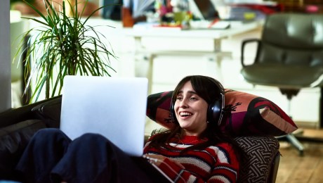 woman laying on a couch studying on her laptop