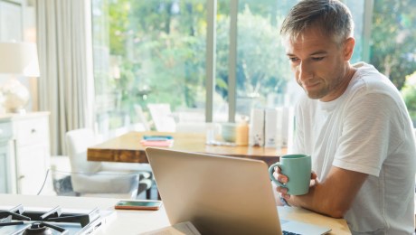 man studying on a laptop while drinking coffee